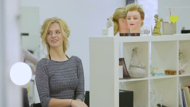 Мила блондинка дивиться у дзеркало в салоні краси — стокове відео