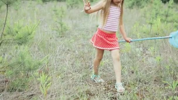 Mała dziewczynka gra na polanie, w pobliżu lasu — Wideo stockowe