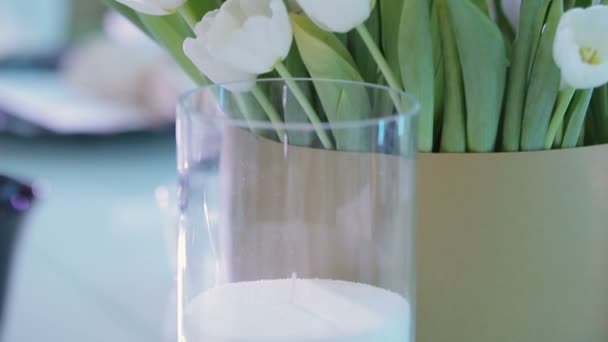 Живі тюльпани на красиво покладеному столі з чорними окулярами — стокове відео
