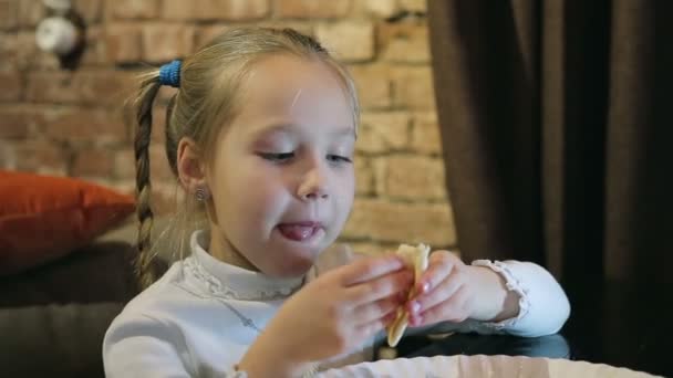 Malá holčička v kavárně je jíst pizzu s rukama — Stock video