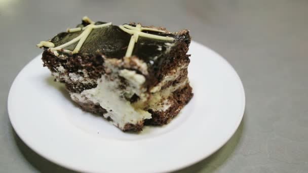 Hand with a spoon breaks off a piece of chocolate cake on a plate — Stock Video