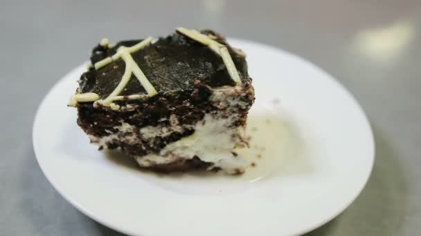 Mano con una cuchara rompe un pedazo de pastel de chocolate en un plato — Vídeos de Stock
