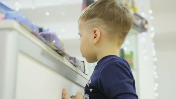 Мальчик смотрит в окно с игрушками — стоковое видео