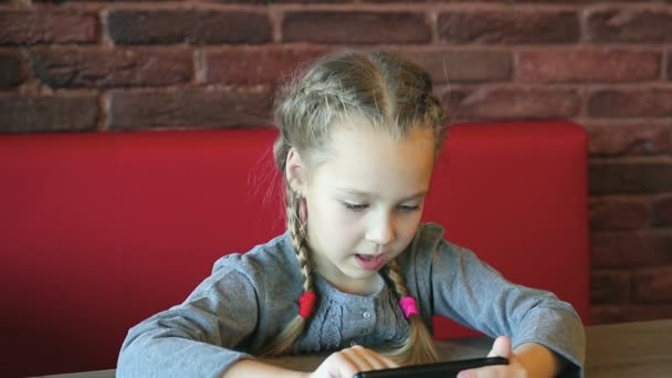 Маленька дівчинка грає зі смартфоном — стокове відео