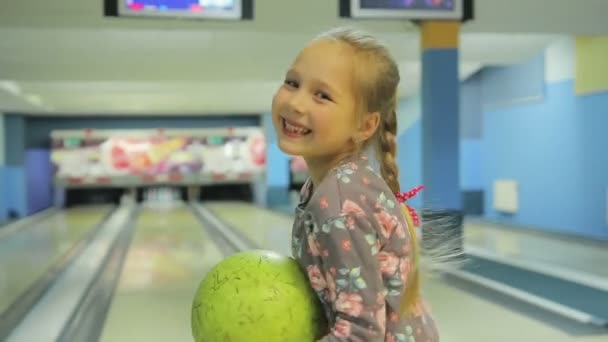 Маленькая забавная девочка играет в боулинг — стоковое видео