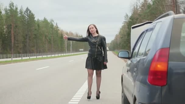 Junge braunhaarige Frau hält für eine Fahrt in der Nähe der kaputten Maschine — Stockvideo
