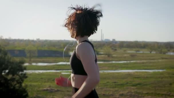 젊은 예쁜 sportswoman 자연 피트 니스에서 관여 된다. 여자는 도시 밖에 서 연습을 수행합니다. Steadicam 샷 — 비디오