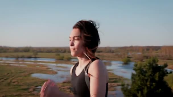 Jovem muito esportista está envolvido na aptidão na natureza. A menina realiza exercícios fora da cidade. Steadicam tiro — Vídeo de Stock