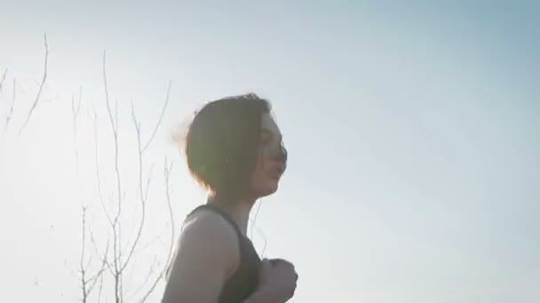 Jeune jolie sportive est engagée dans la remise en forme dans la nature. La jeune fille fait des exercices à l'extérieur de la ville. Steadicam shot — Video