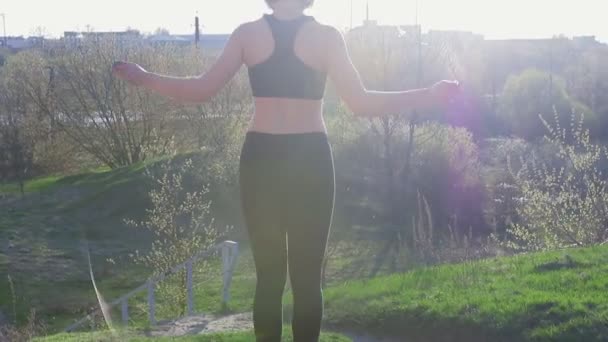 Young pretty sportswoman is engaged in fitness in nature. The girl performs exercises outside the city. Steadicam shot — Stock Video
