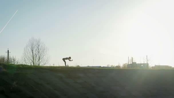 Junge hübsche Sportlerin beschäftigt sich mit Fitness in der Natur. Das Mädchen macht außerhalb der Stadt Übungen. Steadicam-Aufnahme — Stockvideo