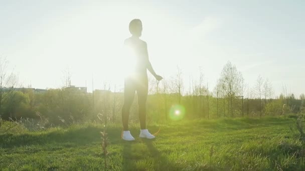 Jeune jolie sportive est engagée dans la remise en forme dans la nature. La jeune fille fait des exercices à l'extérieur de la ville. Steadicam shot — Video