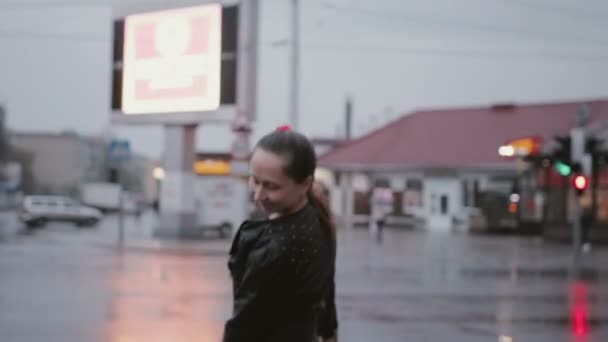 Jovem mulher alegre em jeans rasgado dançando em lajes de pavimentação molhadas — Vídeo de Stock