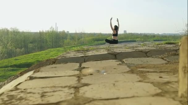 Giovane ragazza carina facendo ginnastica. L'atleta siede su lastre di cemento — Video Stock
