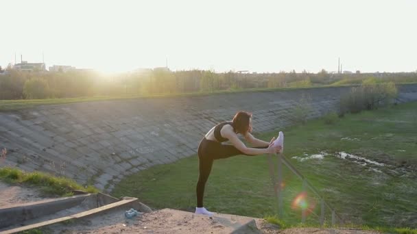 Hübsches junges Mädchen beim Stretching im Hintergrund der untergehenden Sonne — Stockvideo