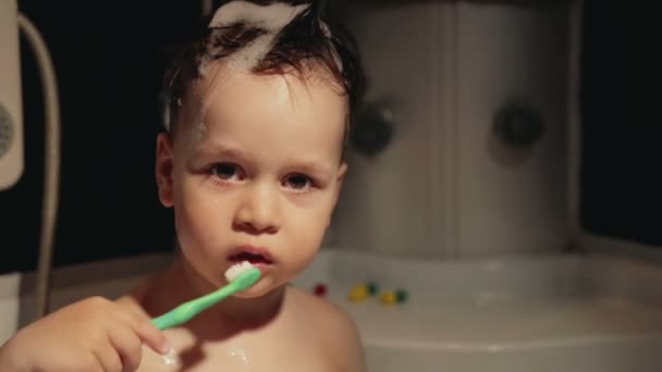 Маленький веселый мальчик 2-3 лет чистит зубы в душе и смеется. — стоковое видео
