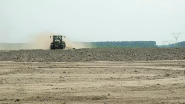 Ein Traktor mit landwirtschaftlicher Maschine verarbeitet den Boden, viel Staub steigt auf — Stockvideo