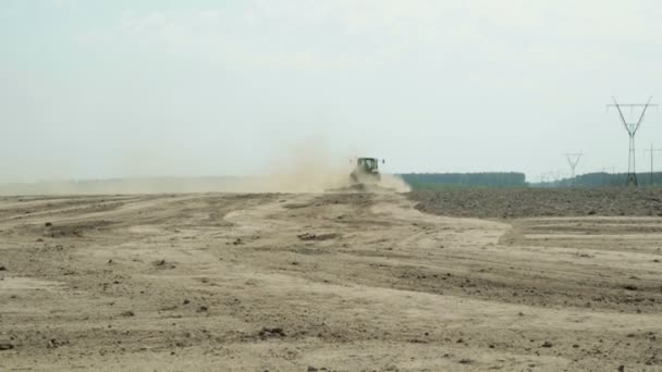 Ένα τρακτέρ με ένα γεωργικό μηχάνημα επεξεργάζεται το χώμα, πολλή σκόνη αυξάνεται — Αρχείο Βίντεο