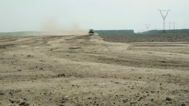 En traktor med en landbruksmaskin behandler jorden, og mye støv stiger. – stockvideo