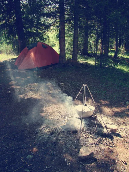 La comida se cocina en un hervidor de agua en un fuego abierto en un campamento forestal — Foto de Stock