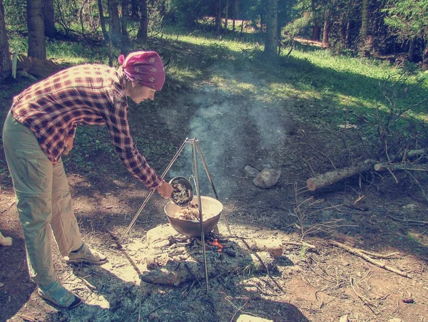 Jonge vrouw koken voedsel verse champignons op een open brand — Stockfoto