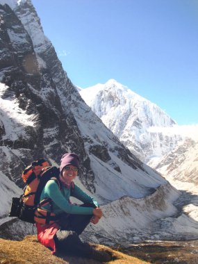 Kız bir sırt çantası ile bir iz karlı arka planda oturur 