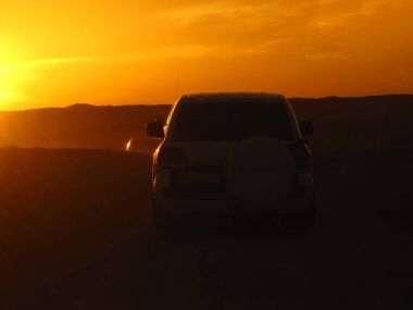 batan güneşin ışınları çölde otomobillerin siluetleri