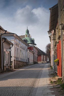 Finlandiya 'da güneşli bir bahar gününde Portvoo Katedrali' ne bakan şehrin tarihi merkezinde dar bir sokakta renkli ahşap evler.