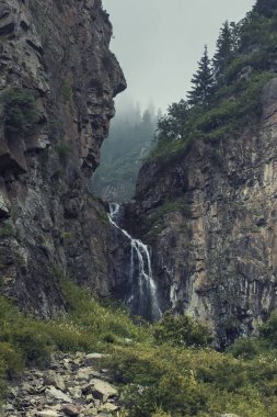 Butakovsky şelalesi Almaty Kazakistan 'daki Zailiysky Alatau dağlarında kayalar ve sisli.