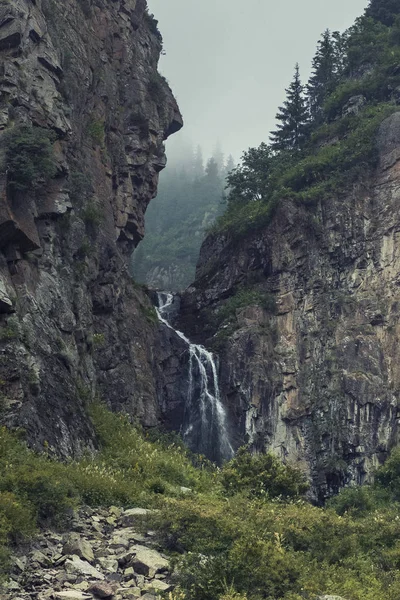 Butakovsky şelalesi Almaty Kazakistan 'daki Zailiysky Alatau dağlarında kayalar ve sisli.