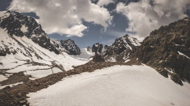 Kazakistan 'ın Almaty kenti yakınlarındaki Tien Shan sisteminin Trans-Ili Alatau dağ sırasının panoraması. Yazın ortasında bulutların altında kar ve buzullarla kaplı Rocky tepeleri.