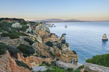  Akşamüstü Portekiz 'in Lagos şehrindeki Atlantik Okyanusu' nun kayalık sahillerindeki kayalıklara, adalara ve merdivenlere.
