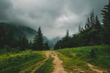 Karanlık bulutların altında dağların arasında yol. Karanlık ruh hali