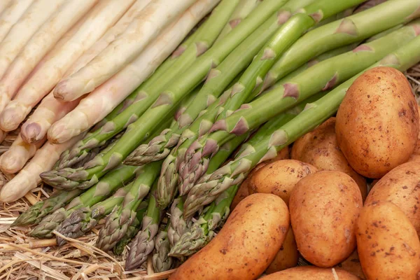 Taze ham organik yeşil ve beyaz kuşkonmaz ve patates saman arka plan üzerinde. Kuşkonmaz officinalis, Solanum tuberosum