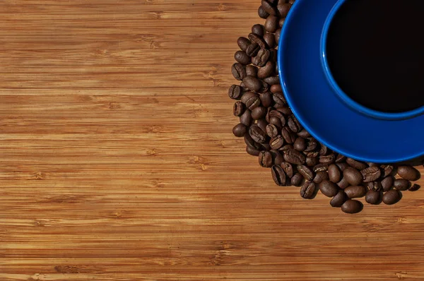 Чашка черного кофе с бобами на деревянном фоне. Вид сверху — стоковое фото