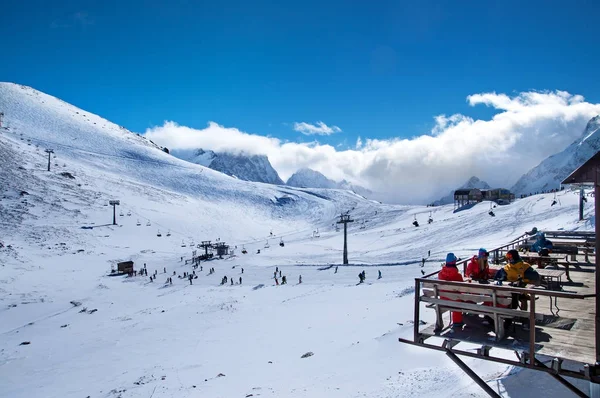 Ρωσία, Dombai-Φεβρουάριος 7, 2017: Όμορφη θέα του χιονοδρομικού ψηλά στο βουνό. Ομάδα φίλων απολαμβάνοντας ζεστό ρόφημα στο Cafe στο χιονοδρομικό θέρετρο — Φωτογραφία Αρχείου