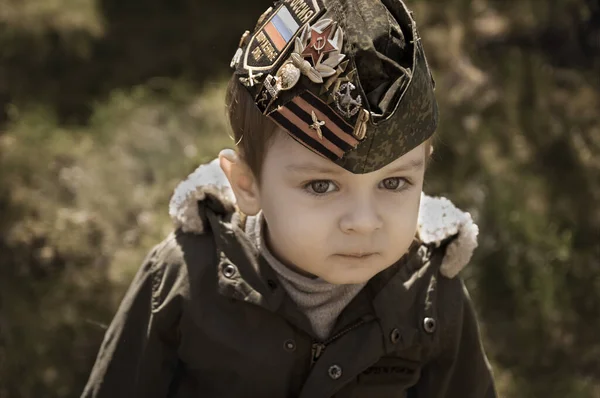 9 Mayıs 'ta Rusya' da, Zafer bayramında, 2. Dünya Savaşı madalyası ve madalyası olan askeri şapkalı küçük bir çocuk. Telifsiz Stok Imajlar