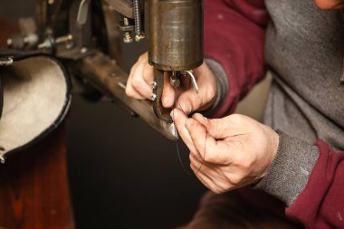 Dikiş makinesine iplik sokan kunduracının ellerine yakın çekim