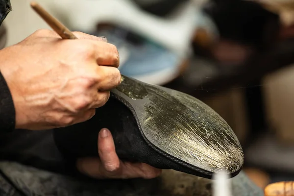 close-up of a male shoemaker's shoe glueing the sole of a shoe
