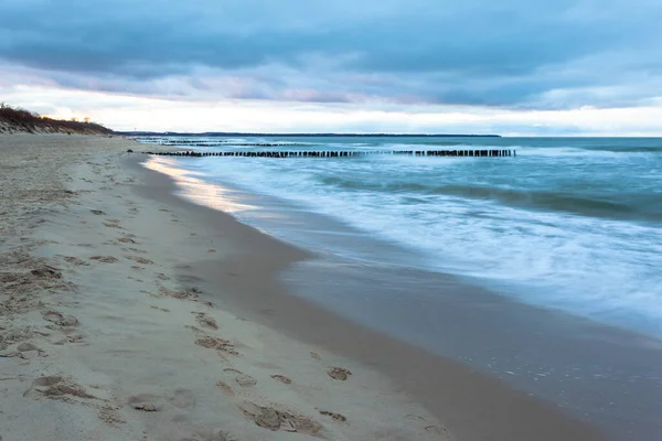 长期暴露在阴天的蓝色黄昏 沙滩上 在寒冷的海面上有防波堤 — 图库照片