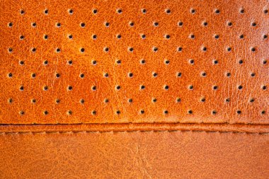 Küçük delikli parlak kahverengi deri yüzey ve bir dikiş, arka plan, doku