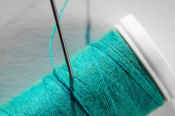 blue thread reel with needle stuck in macro