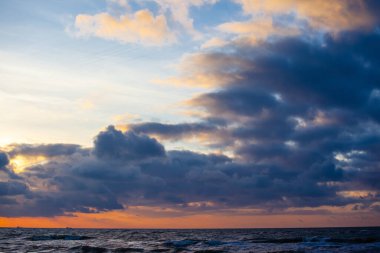 Gün batımında denizin üzerinde renkli parlak bulutlar