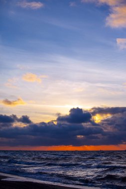 Gün batımında denizin üzerinde renkli parlak bulutlar
