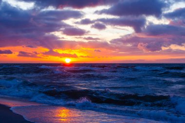 Renkli bulutlar ve gün batımında parlak güneş ışığı ile resim gibi deniz manzarası