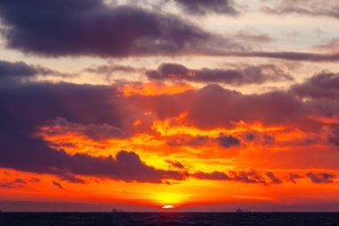 Renkli bulutlar ve gün batımında parlak güneş ışığı ile resim gibi deniz manzarası