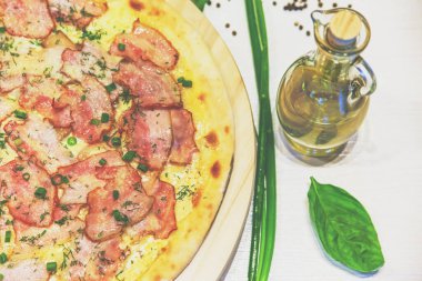 Pastırmalı pizza, yeşil soğan ve beyaz bir masada zeytinyağı, retro tonlu.