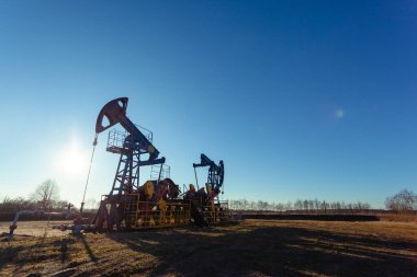 Parlak güneş ve mavi gökyüzüne karşı çalışırken petrol üretim kulesi