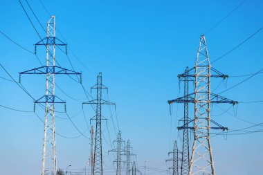 Mavi gökyüzüne karşı elektrik hatları.