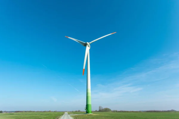 Turbina Wiatrowa Wśród Zielonego Pola Przeciw Błękitnemu Niebu — Zdjęcie stockowe